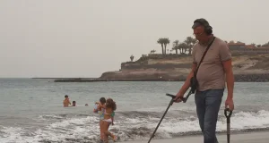 Beach Treasure Hunting: Essential Gear Man with metal detector on a beach
