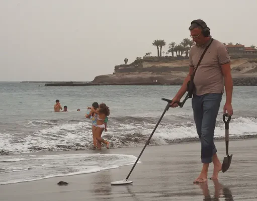 Beach Treasure Hunting: Essential Gear Man with metal detector on a beach