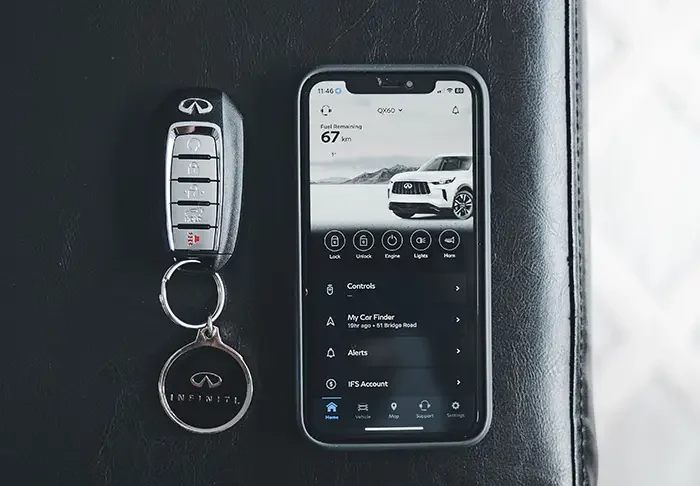 A car key fob lying on gravel beside the wheel of a parked car