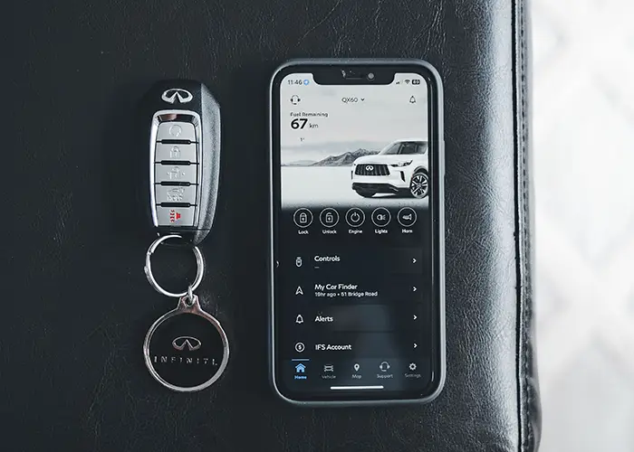 A car key fob lying on gravel beside the wheel of a parked car