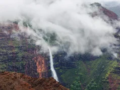 Places to Visit in Lonavala: Best Attractions & Where to Stay A scenic view of a tall waterfall cascading down a steep mountain landscape covered in green foliage.