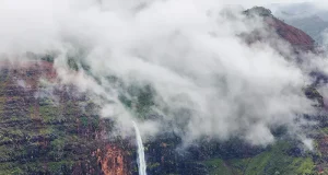 Places to Visit in Lonavala: Best Attractions & Where to Stay A scenic view of a tall waterfall cascading down a steep mountain landscape covered in green foliage.