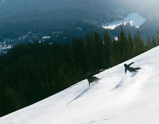 Why LAAX Deserves a Place on Your Swiss Ski Shortlist Skier and snowboarder descending a snowy slope at LAAX ski resort in the Swiss Alps