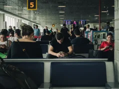 Best eSIM for International Travel in 2026 People seated in a São Paulo airport terminal looking at their phones while waiting