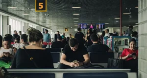 Best eSIM for International Travel in 2026 People seated in a São Paulo airport terminal looking at their phones while waiting