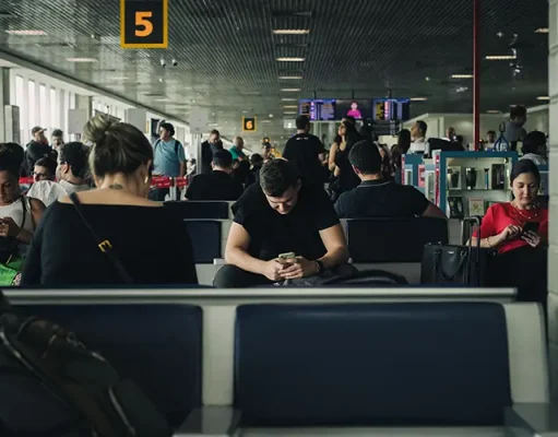Best eSIM for International Travel in 2026 People seated in a São Paulo airport terminal looking at their phones while waiting