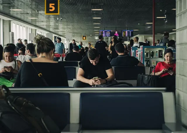 People seated in a São Paulo airport terminal looking at their phones while waiting
