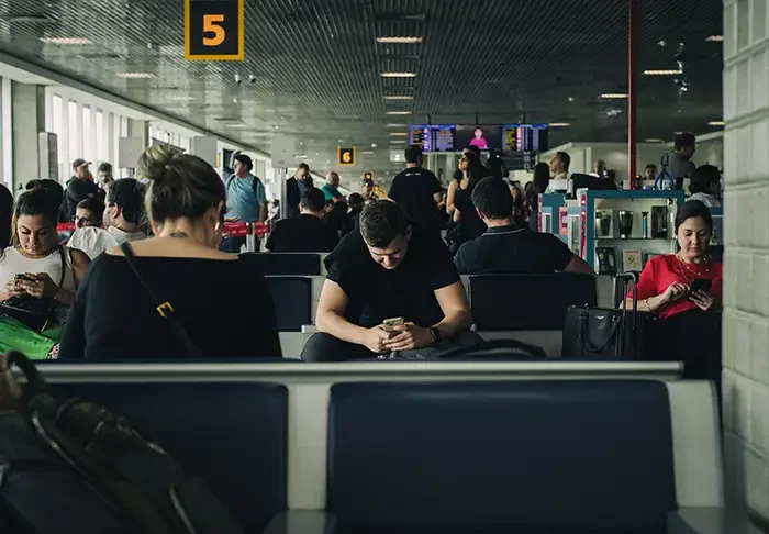 People seated in a São Paulo airport terminal looking at their phones while waiting