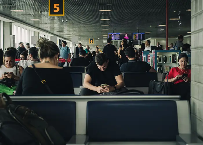 People seated in a São Paulo airport terminal looking at their phones while waiting