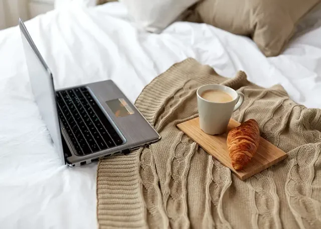 coziness-technology-interior-winter-concept-cozy-bedroom-with-laptop-computer-coffee-cup-croissant-bed-home copy