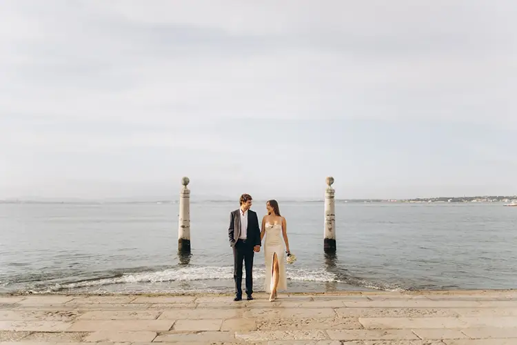 Bride and groom on the Cais das Colunas steps into the Tagus at Praça do Comércio, Lisbon