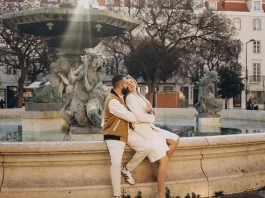 Couple sitting on the rim of the baroque fountain in Rossio square, Lisbon