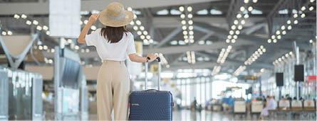 Young woman hand holding luggage handle before checking flight time in airport, Transport, insurance, travel and vacation concepts