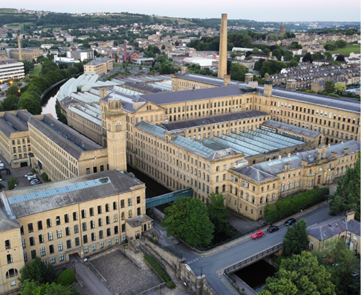 An aerial shot of cityscape Saltaire with Salts Mill building in daylight
