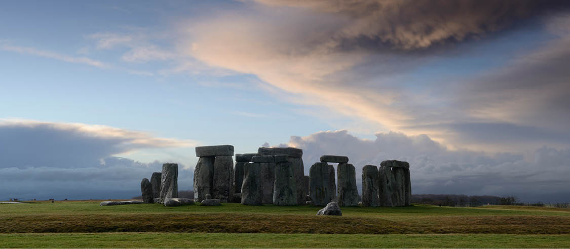 Stonehenge is a pre-historic henge and national landmark on the Wiltshire plain  It is a stone circle of standing stones, with some stones placed horizontally across the top of vertical stones  It is a UNESCO world heritage site  Gathering clouds over the site 