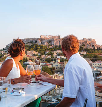 Couple drinking and enjoying the view of the Acropolis at sunset. Athens, Greece