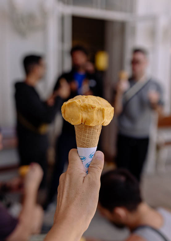 A person holding a cone of ice cream. Description generated by AI