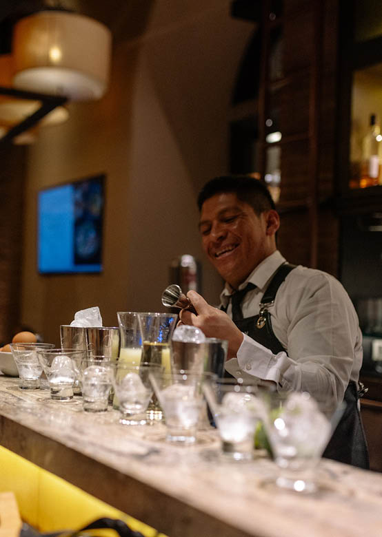 A man is smiling at the camera while standing behind a bar. Description generated by AI