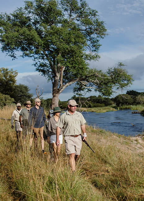 A group of people walking on a path near a river. Description generated by AI
