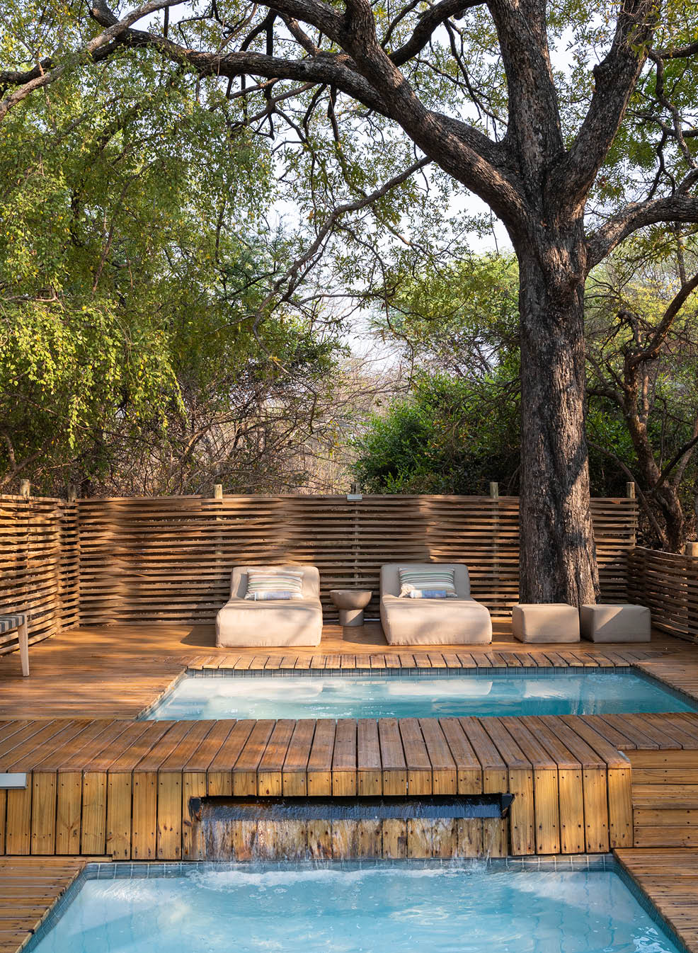 A wooden deck with a pool and a tree in the background. Description generated by AI