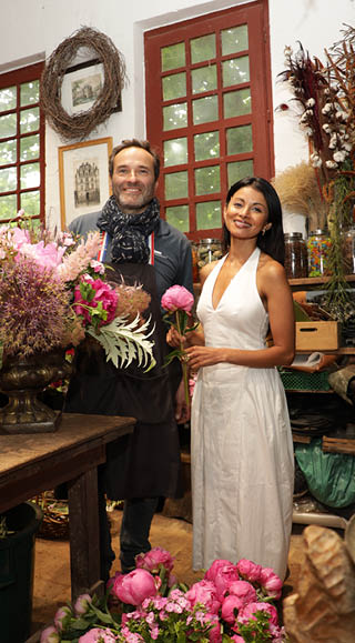 A man and a woman are standing in front of a flower shop. Description generated by AI