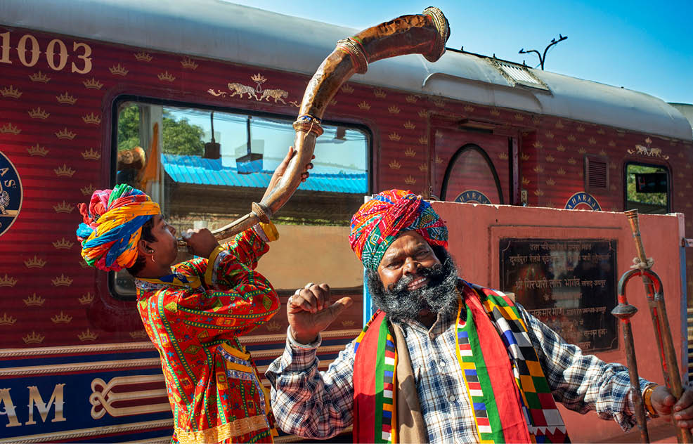 A man in a colorful outfit is holding a large horn. Description generated by AI