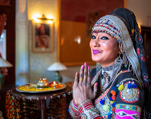 A woman wearing a colorful dress and a headpiece is smiling. Description generated by AI