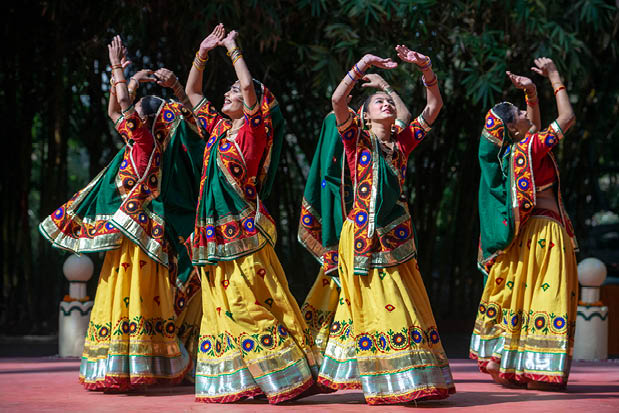 Four women wearing colorful dresses and dancing. Description generated by AI