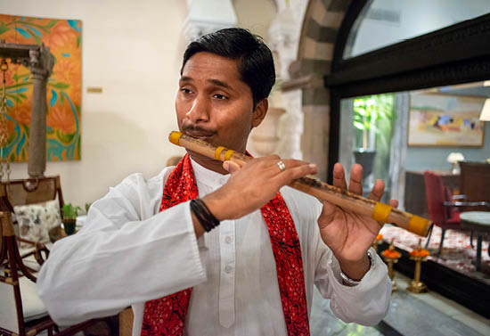 A man wearing a white shirt and red scarf is playing a musical instrument. Description generated by AI