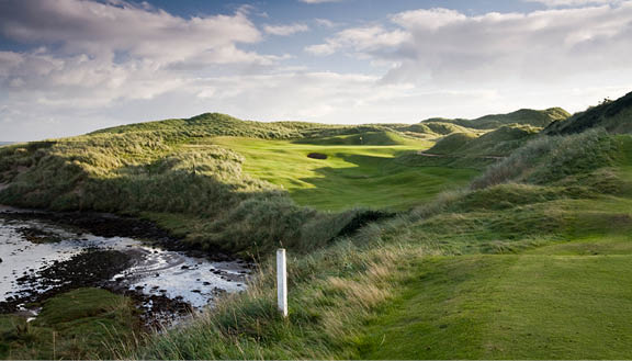 A green golf course with a white sign. Description generated by AI