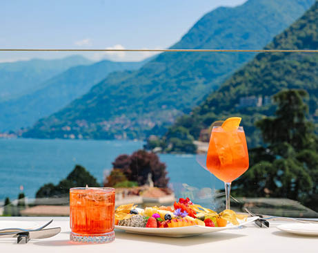 A table with a plate of fruit and a glass of orange juice. Description generated by AI