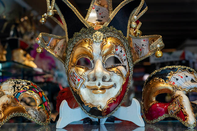 Ornate carnival mask among colorful feathers in Venice, Italy. A display of Masquerade Ball Masks and Venetian Mask on sale in Bardolino Lake Garda Veneto Region Italy 