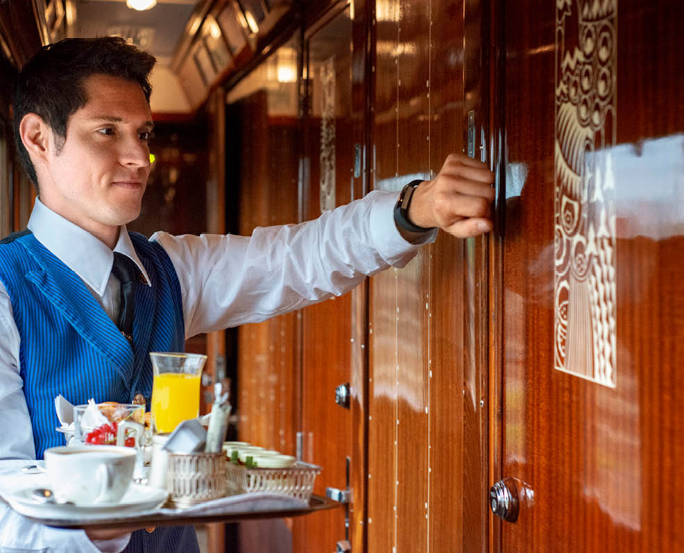 A waiter serves breakfast in one of the single compartment inside the train Belmond Venice Simplon Orient Express luxury train near Paris An icon of art deco design. Rekindle the romance of the rails as you travel between Europe’s most captivating cities. The Venice Simplon-Orient-Express, or VSOE, is a private luxury train service from London to Venice and other European cities. It is currently owned by Belmond, which operates 45 luxury hotels, restaurants, tourist trains and river cruises in 24 countries. It was agreed in December 2018 for the service to be acquired by LVMH 