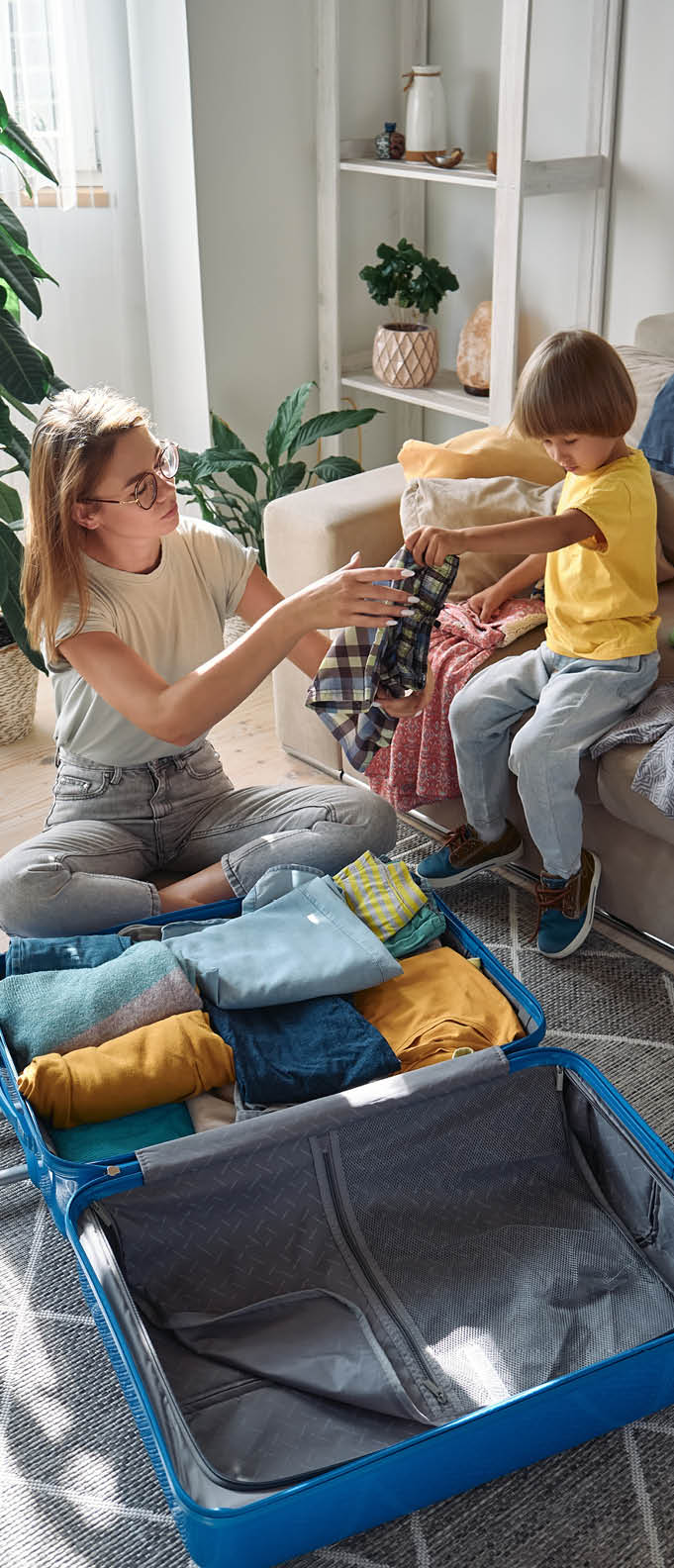 Family mother and child packing a suitcase together going on a trip or vacation.