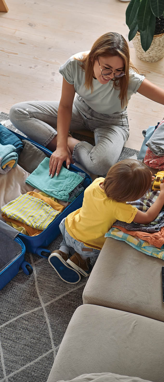 Family going on a trip or vacation, mother packing a suitcase, child playing next to a toy car.