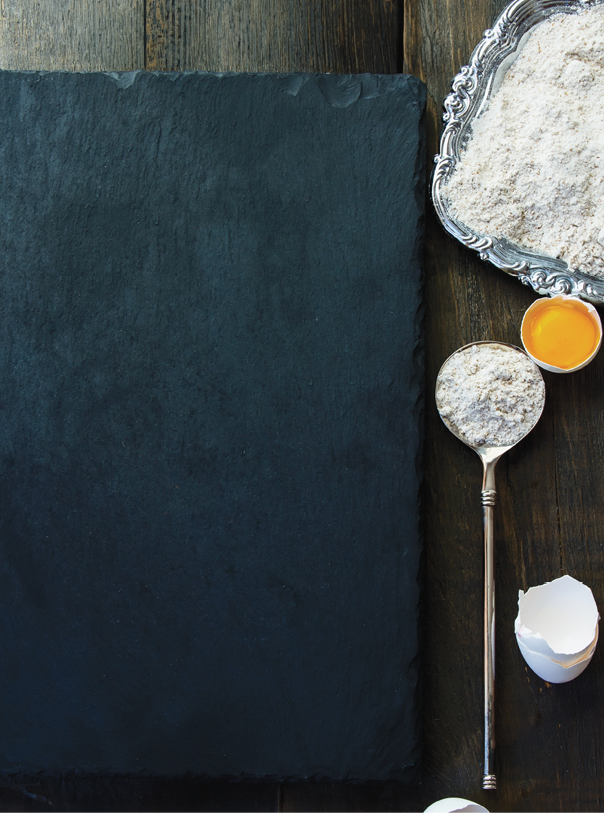Baking background with raw eggs, eggshell, cinnamon and flour. Top view. Slate and wood background. Lots of copyspace.