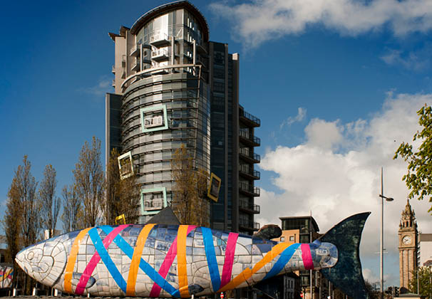 The Big Fish sculpture by John Kindness, Donegall Quay, River Lagan, Belfast, Northern Ireland, UK. Back, The Boat Office building. The Big Fish also called the Bigfish is a printed ceramic mosaic sculpture by John Kindness 10 metres long constructed in 1999 in Donegall Quay in Belfast, near the Lagan Lookout and Custom House. 