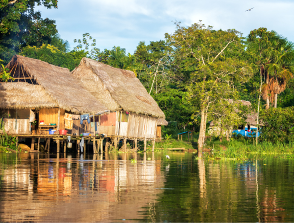 Late afternoon view of a shack on stilts in the Amazon rain forest with a beautiful reflection in the river