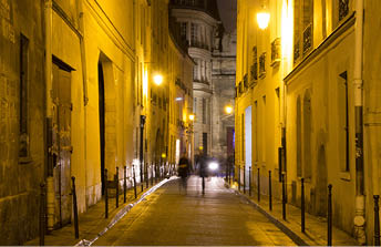 Two women walk in blurry motion at night on one of the streets of Le Marais district in Paris  It's night time  The district hosts many outstanding buildings of historic and architectural importance