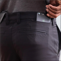 A man wearing a gray shirt and black pants is holding his phone in his pocket. AI generated content