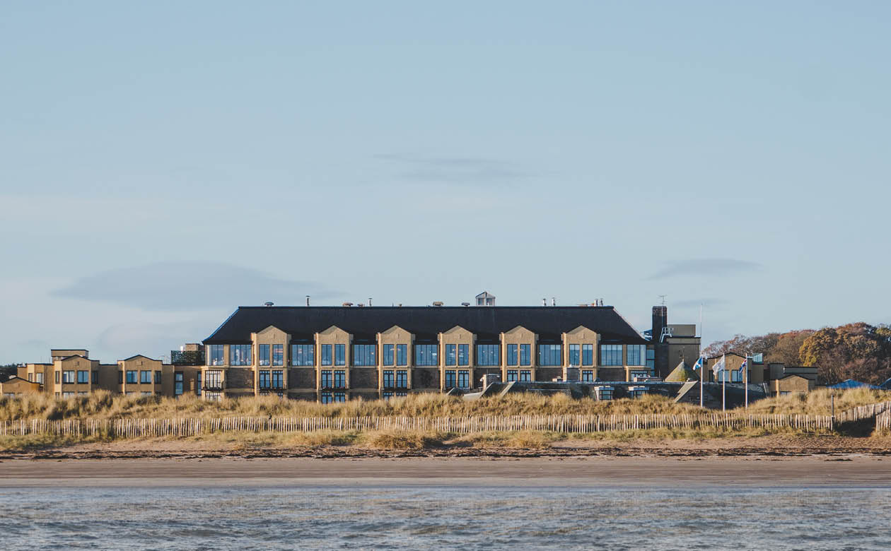 A large house sits on a sandy beach, overlooking a body of water. AI generated content