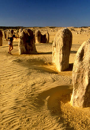 A woman is standing in front of a row of large rocks. AI generated content