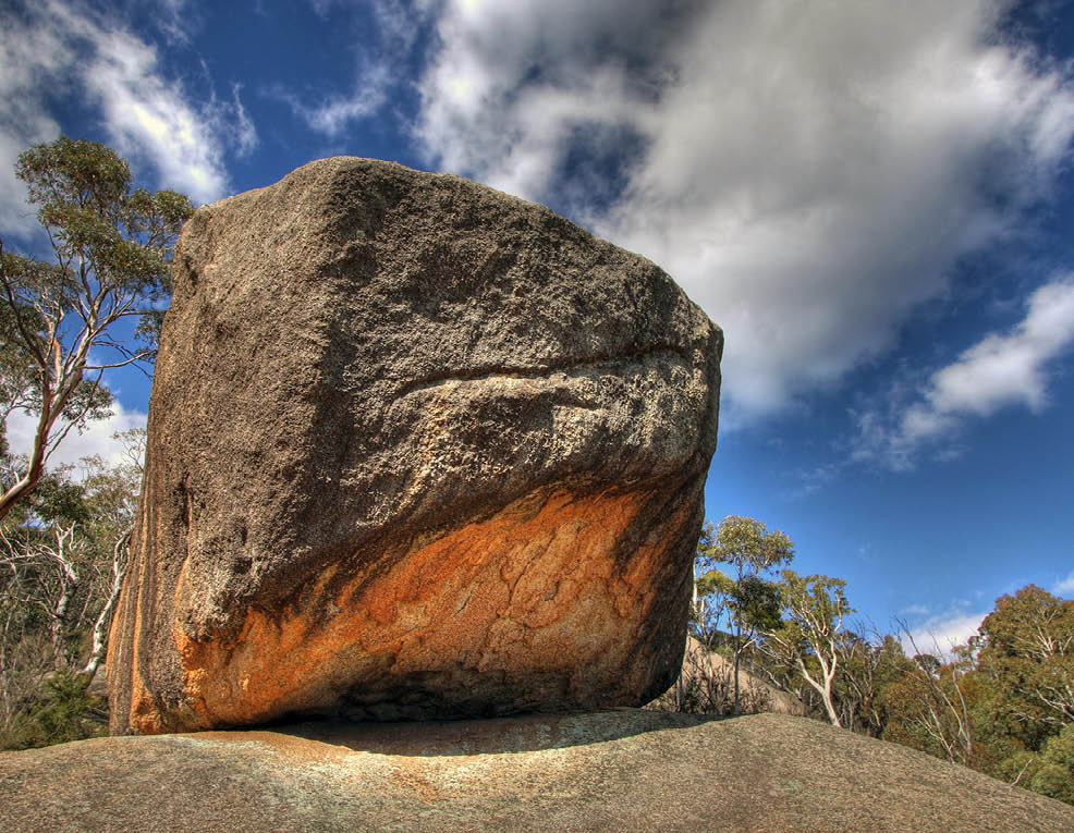 A large rock with a reddish hue is sitting on a rocky surface. AI generated content