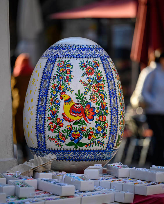 A large, colorful egg is displayed on a table, surrounded by other decorative items. AI generated content