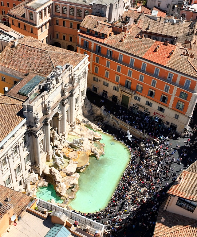 A large crowd of people gathered in a city square, with a large green pool in the center. The square is surrounded by tall buildings, and there is a fountain nearby. AI generated content