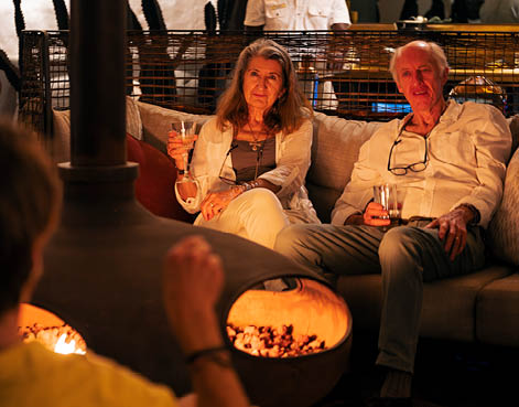 A man and a woman are sitting on a couch, holding wine glasses. AI generated content