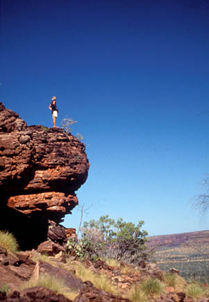 A person is standing on a rocky cliff overlooking a valley. AI generated content