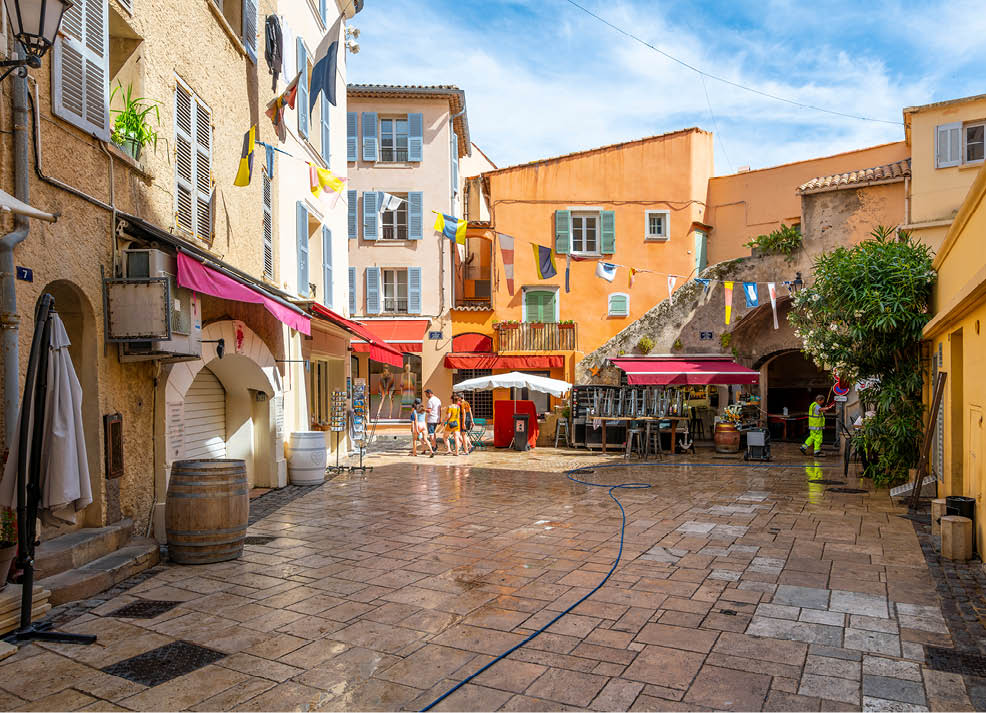 A narrow street in a city with a red awning and awnings on the buildings. AI generated content