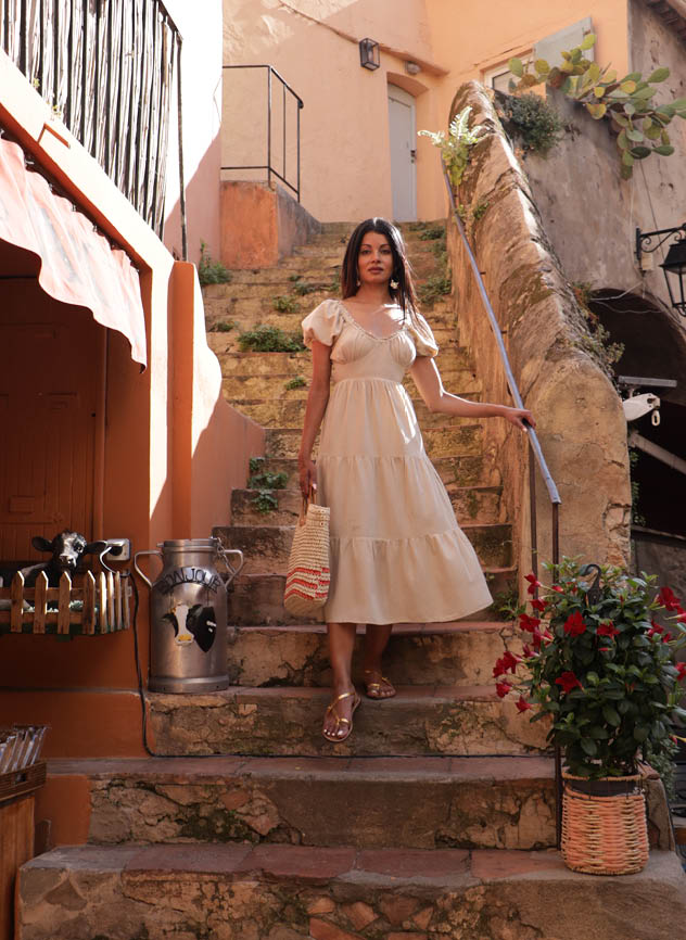 A woman in a white dress is standing on a stone staircase. AI generated content