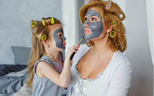 Happy mother and daughter with black face masks in the bedroom on the bed  The concept of home entertainment 